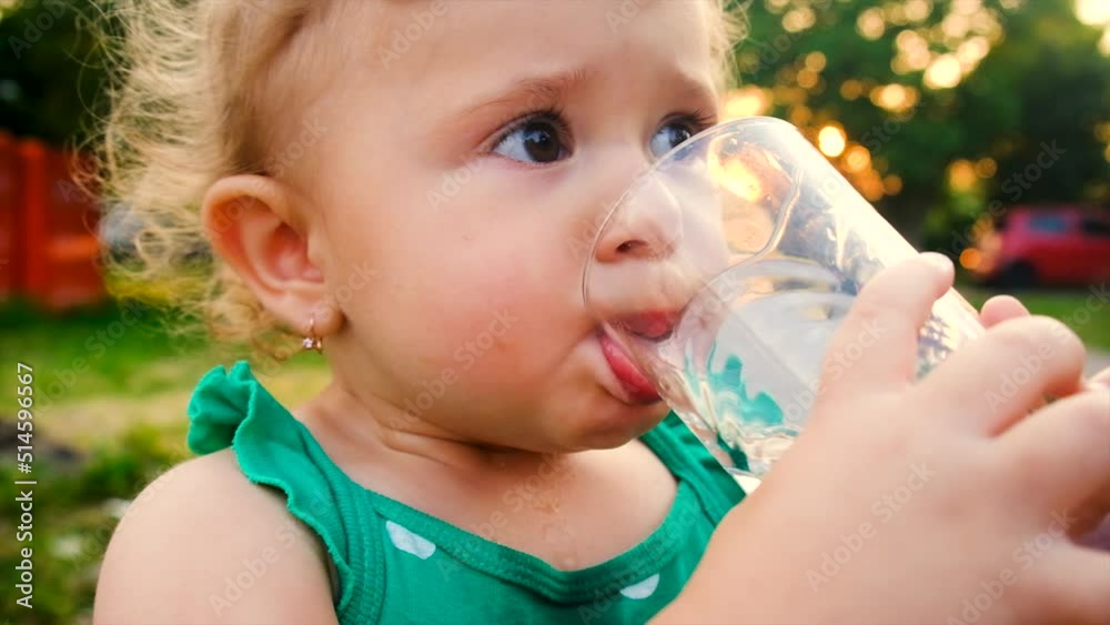 The child drinks water from a glass. Selective focus. The child drinks water from a glass. Selective focus.