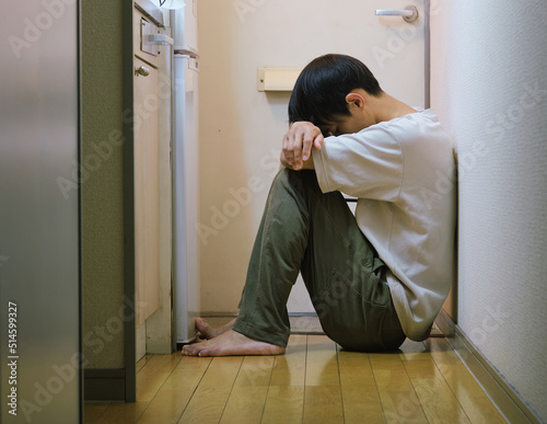 asian boy alone sad in small apartment room with lights on