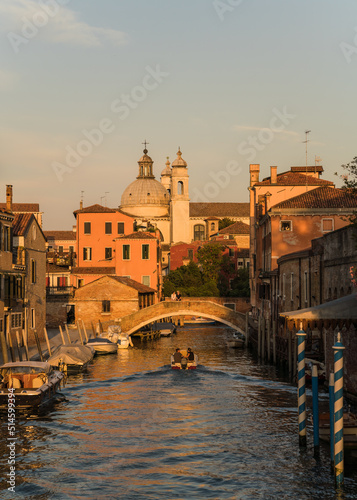 architectural detail of an old bridge in Venice, Italy over a canal and typical architecture on the background and boat passing by 