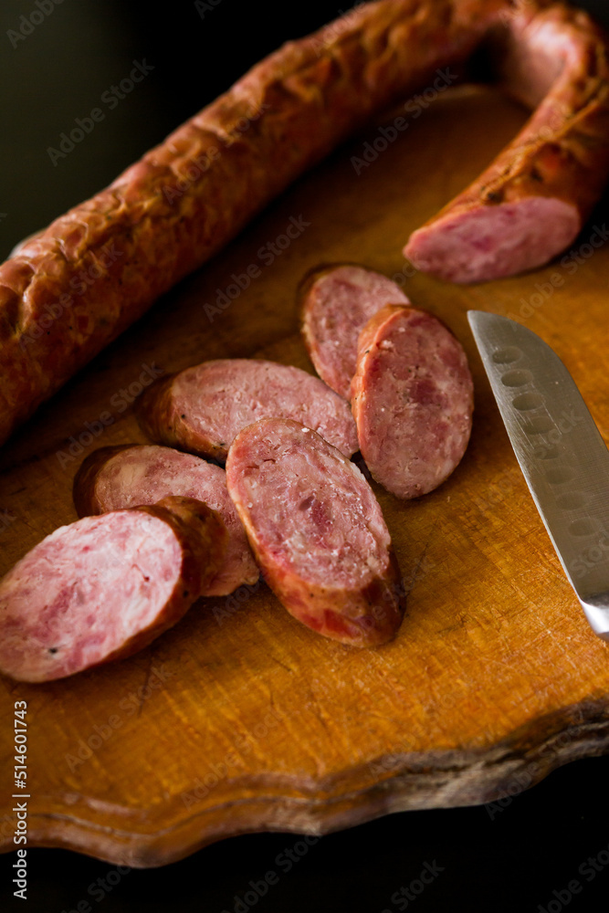 salami on board. Basket with sausages and greens. Meat products. Bacon, sausage and ham in a basket with vegetables on a black background. salami on board. Basket with sausages and greens. Meat products. Bacon, sausage and ham in a basket with vegetables on a black background.