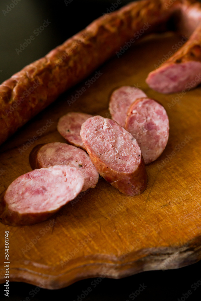 salami on a board. Basket with sausages and greens. Meat products. Bacon, sausage and ham in a basket with vegetables on a black background. salami on a board. Basket with sausages and greens. Meat products. Bacon, sausage and ham in a basket with vegetables on a black background.
