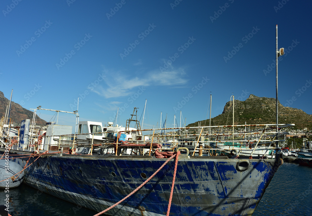 A weathered trawler in Hout Bay harbor in the Western Cape South Africa with the Sentinel peak in the background
