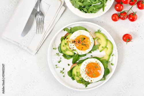 Bread with fried eggs, avocado and greens