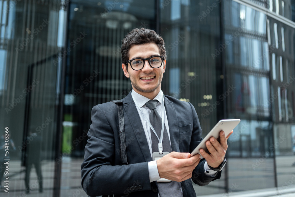 The manager uses a tablet to write a communication message to a colleague, a man with glasses goes to the office to work, in a business suit