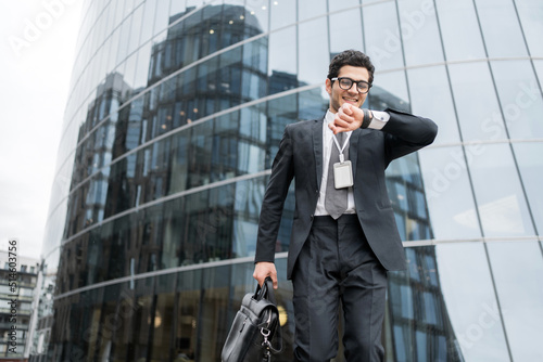 The manager looks at the clock a man with glasses goes to the office to work, in a business suit