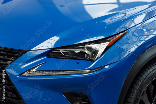 Close-up headlights of a modern blue color car. Detail on the front light of a car. Modern and expensive car concept. The car is in the showroom. Automotive concept. Classic blue color. LED light
