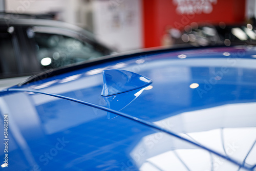 Close-up GPS antenna shark fin shape on a roof of car for radio navigation system. Antenna shark fin on blurry background. Car detail. Classic blue color car. Soft blur background