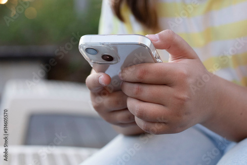 Modern smartphone in the hands of young girl. Typing  hands, mobile phone. Concept of influencer, follower, social media, online shopping, app, digital marketing, chat. Life style. Soft focus. Outside