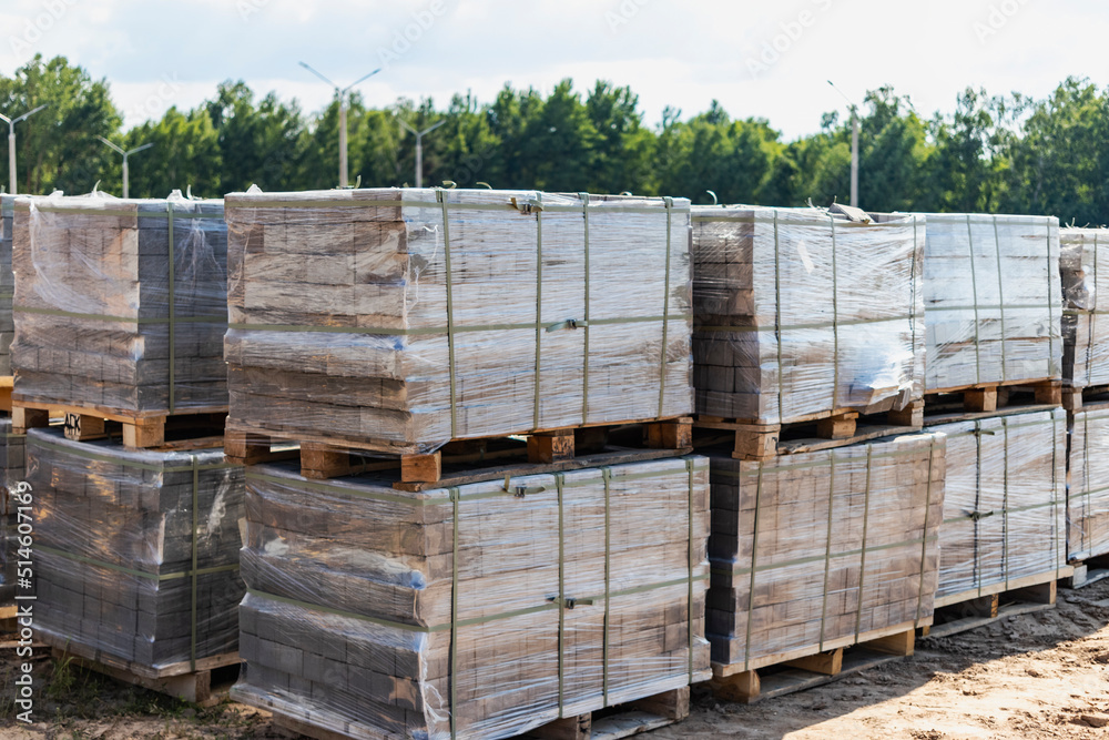 Storage of paving slabs on pallets at the construction site. Ready-to-install concrete paving slabs. Finished products warehouse. Storage of paving slabs on pallets at the construction site. Ready-to-install concrete paving slabs. Finished products warehouse.