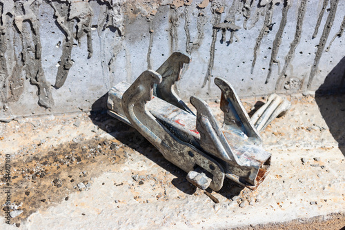 Steel clamps or waler brackets holding forms or forming panels during formwork on construction building site. Concrete cement wall pouring. Rough texture surface. photo