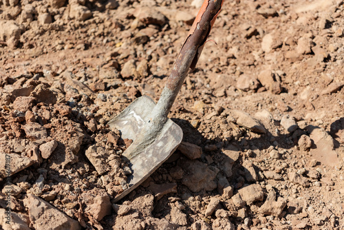 Scoop shovel smeared in concrete in a pile of sand for making concrete.