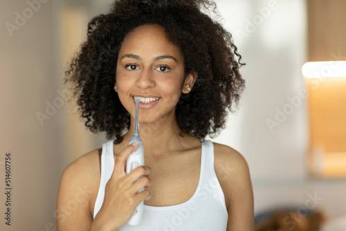 Beautiful woman brushing her teeth with an irrigator looking at the camera