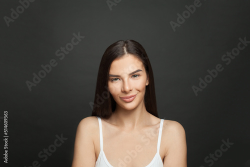 Perfect young woman with clean skin and cute smile on black background