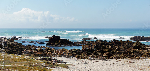 rocky, grassy and sandy colored coast of the blue Indian ocean in the south of South Africa