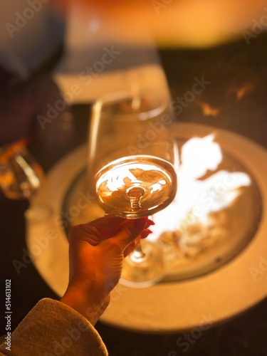 Woman holding wine glass by the fire pit at night