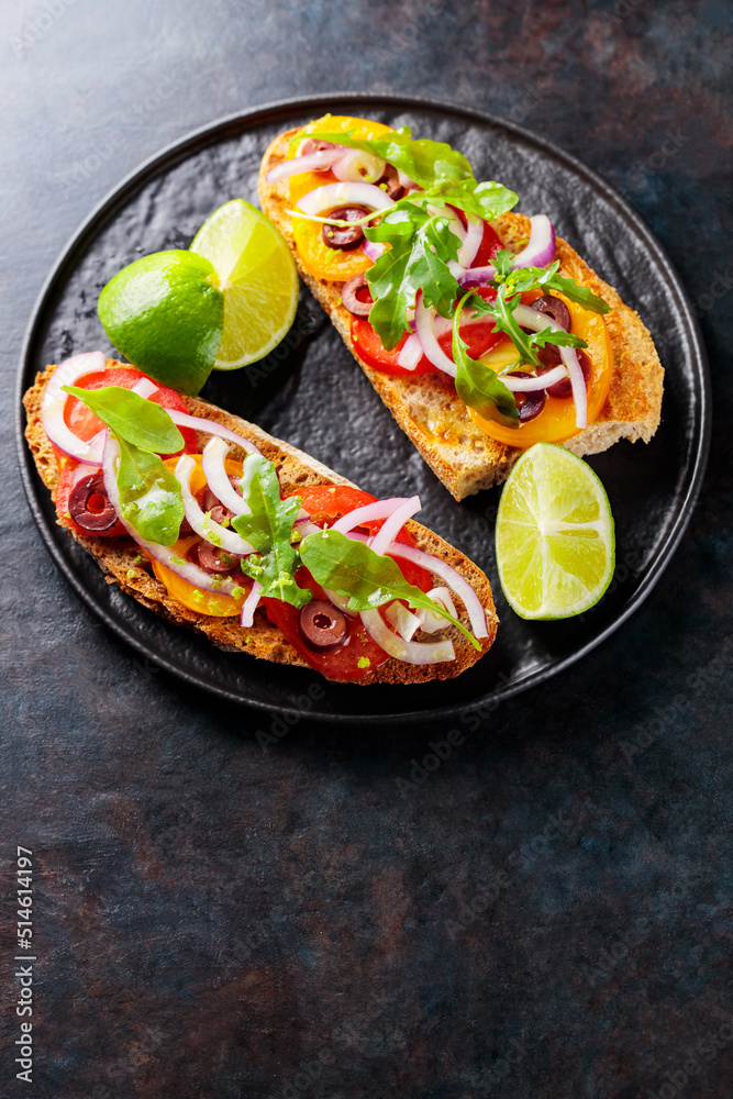 Vegetarian sandwiches on a dark background. Spanish tapas with vegetables, greens, olives and lime. Healthy sandwiches on a black plate. Top view. Copy space Vegetarian sandwiches on a dark background. Spanish tapas with vegetables, greens, olives and lime. Healthy sandwiches on a black plate. Top view. Copy space