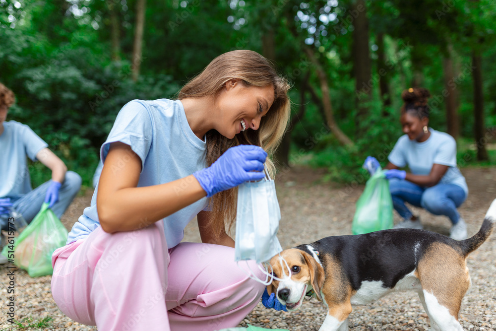 Young woman with her dog waste collector busy separating medical or PPE waste from plastic garbage during the covid-19 coronavirus pandemic Young woman with her dog waste collector busy separating medical or PPE waste from plastic garbage during the covid-19 coronavirus pandemic