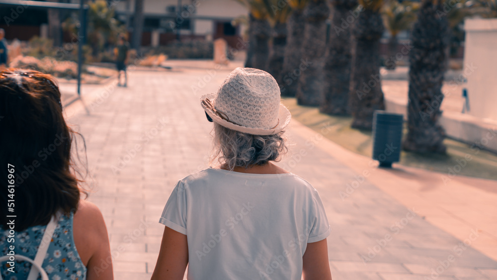 mujer con un sombrero blanco paseando por un paseo de la costa en pleno verano mujer con un sombrero blanco paseando por un paseo de la costa en pleno verano