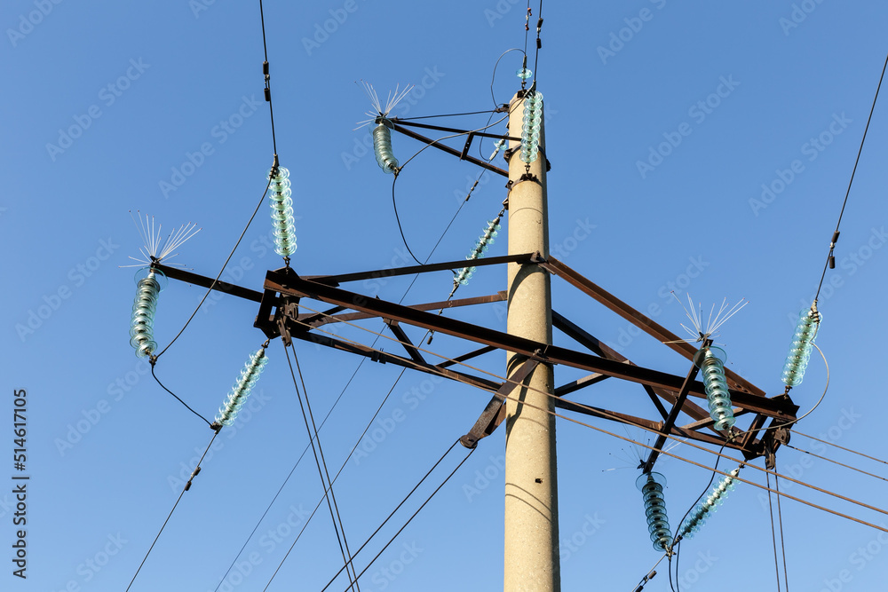 Concrete electricity pylon with glass insulators and bird spikes. Electric power concept. Bird protection for power lines. Concrete electricity pylon with glass insulators and bird spikes. Electric power concept. Bird protection for power lines.