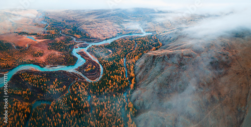 Panoramic view of Chuya river in Kurai steppe, Altai mountains, Siberia, Russia. Aerial drone view. Blue river with yellow autumn trees with morning fog.