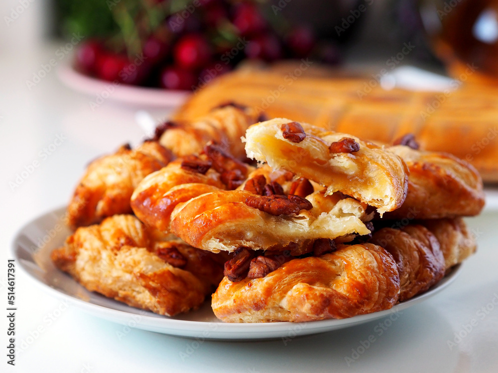 Fresh puff pastry buns with nuts. In the background are cherries, a kettle of tea.