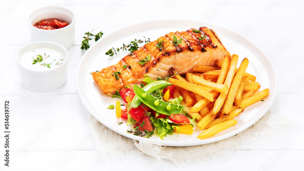 Salmon steak with vegetables and fries on light background. Salmon steak with vegetables and fries on light background.