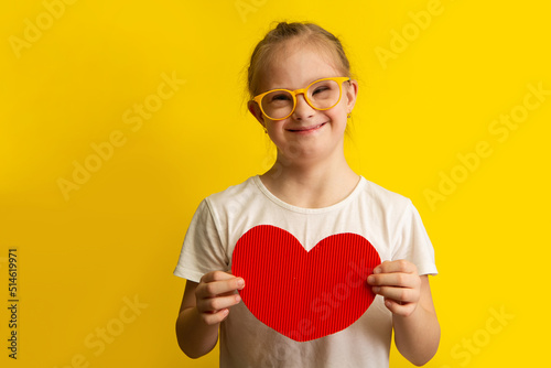 Girl with Down Syndrome holding a big red paper heart