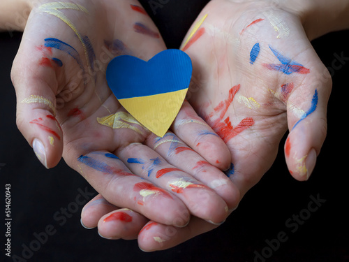 Woman hands painted colorful paints with heart colored Ukrainian flag blue and yellow colors