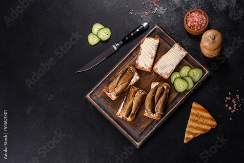 Delicious fresh sandwich with sprats with crispy toast, butter and cucumber