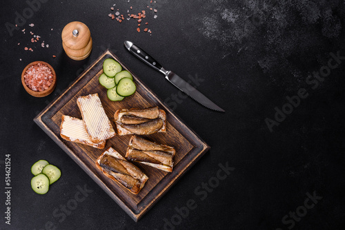 Delicious fresh sandwich with sprats with crispy toast, butter and cucumber photo