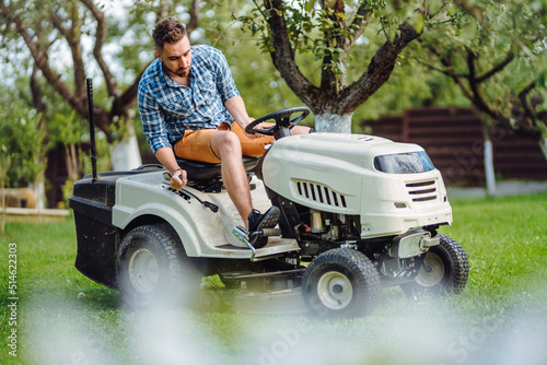 Gardening works with handsome man using lawn mower, tractor and industrial tools