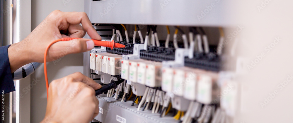 Electrical engineer using measuring equipment to checking electric current voltage at circuit breaker and cable wiring system , Electrical service concept .