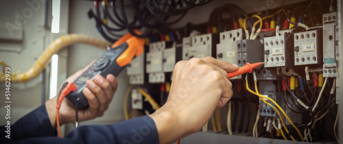 Electrical engineer using measuring equipment to checking electric current voltage at circuit breaker and cable wiring system   Electrical service concept .