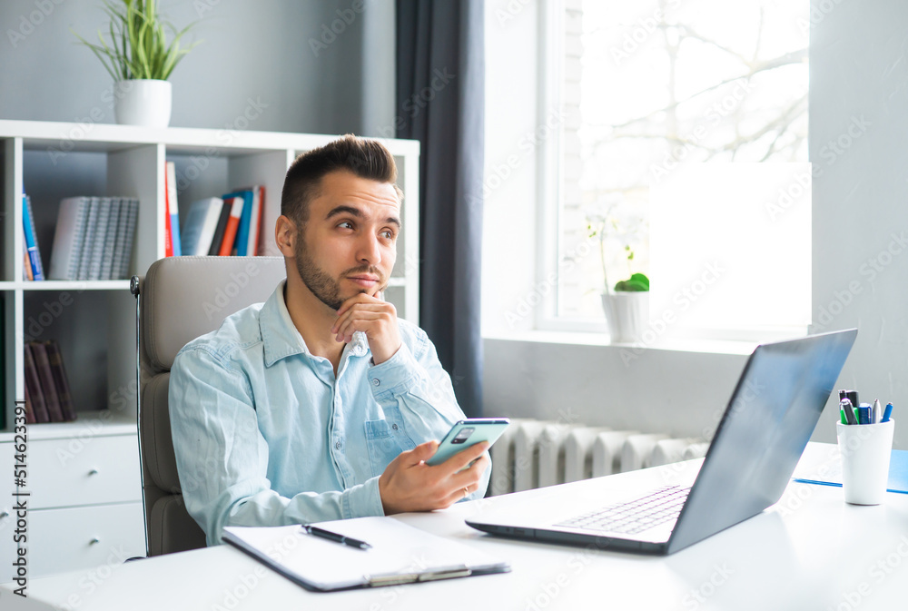 Young Man Works while Sitting in front of a Computer at Home. The Workplace of a Professional Worker, Freelancer or Student. Distance Work and Education Concept. Young Man Works while Sitting in front of a Computer at Home. The Workplace of a Professional Worker, Freelancer or Student. Distance Work and Education Concept.