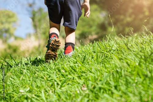 boy walking on the meadow with mountain boots. trekking concept.