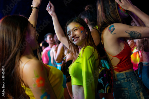 Group of Asian woman having fun celebrating and dancing together at full moon night party at koh phangan beach in Thailand. Happy female friends enjoy outdoor activity lifestyle on summer vacation