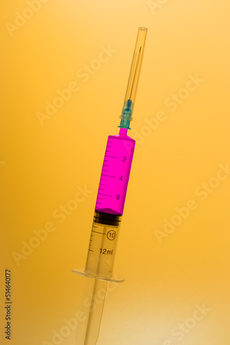 Obraz na płótnie Medical syringe with legendary purple vaccine against corona virus and monkeypox on a yellow background