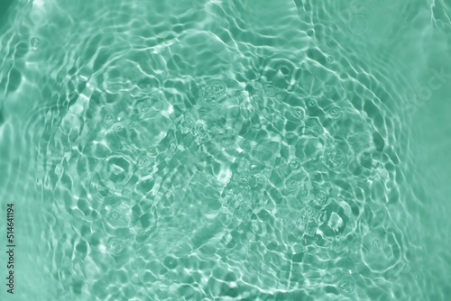 Soft focus lite green blue gray cosmetic moisturizer floral water, micellar toner, or emulsion abstract background. Reflections of scattered sun texture.