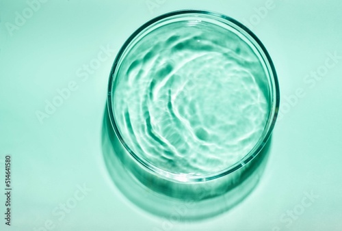 Blue green cosmetic liquid on Petri dish. Tonic or toner serum gel swath. Mock up