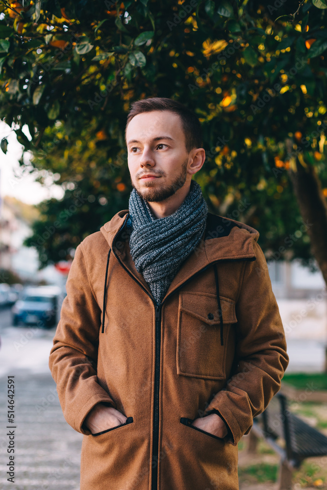 Fototapeta premium close-up guy in a jacket on a background of orange tree and street. portrait.