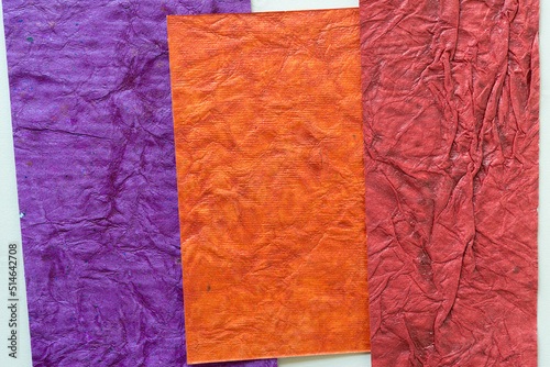 three pieces of colorful paper with texture  purple  orange  and red 