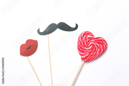 mustache and lips for a photo booth with a heart-shaped lollipop on a white background. Romance, falling in love concept © splitov27