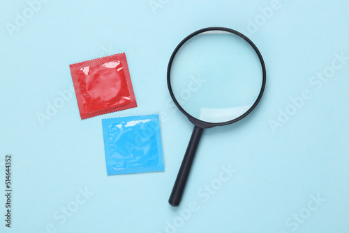 Seeking sexual connections. Condom with a magnifying glass on a blue background