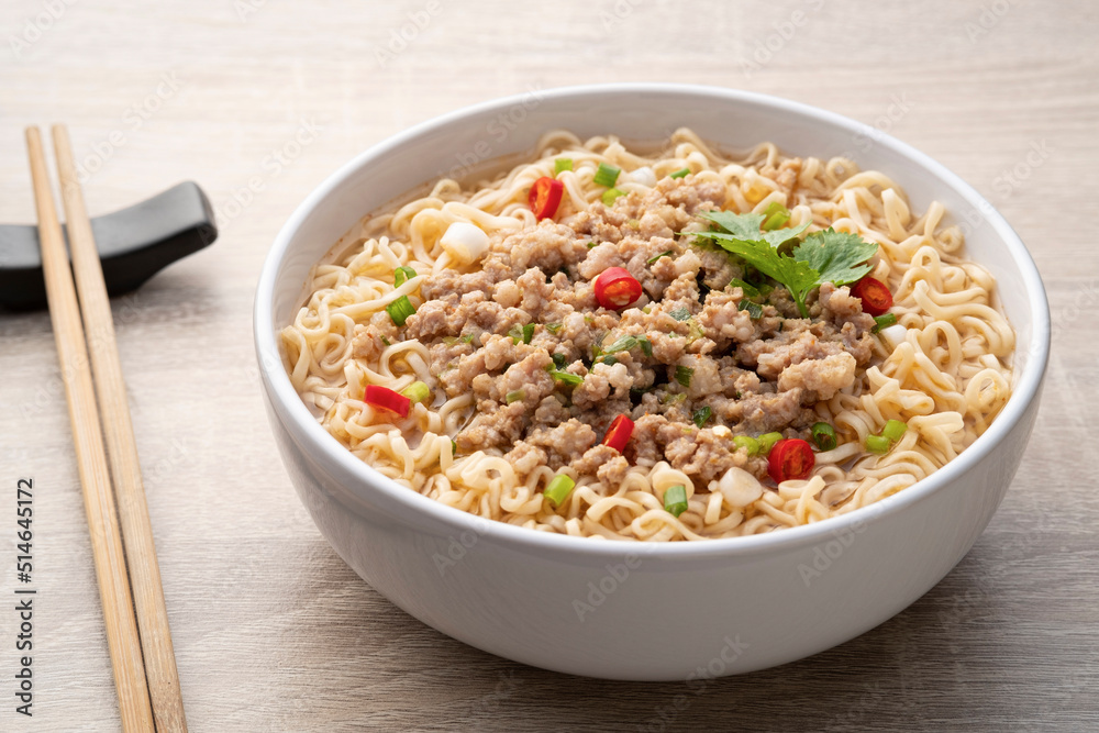 Instant noodle soup with minced pork in white bowl on wood table Instant noodle soup with minced pork in white bowl on wood table