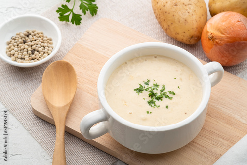 Bowl of creamy potato soup on wooden plate