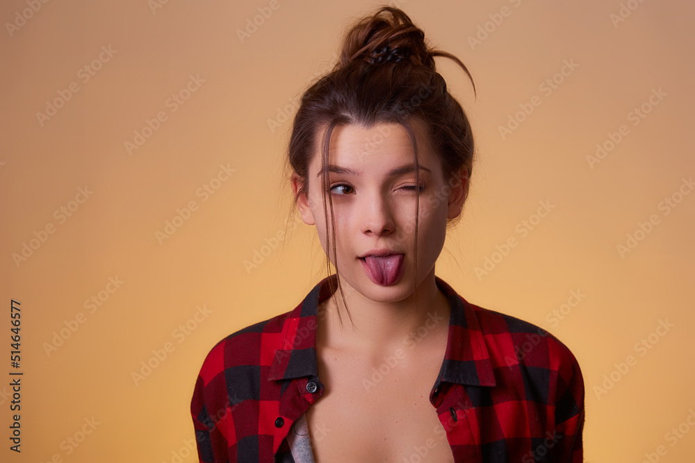 Close up portrait of playful and sweet woman showing tongue giving wink isolated yellow background with copy space for text