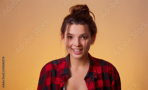 Attractive brunet in red checkered shirt posing isolated on yellow background studio portrait. People sincere emotions lifestyle concept. Mock up copy space.