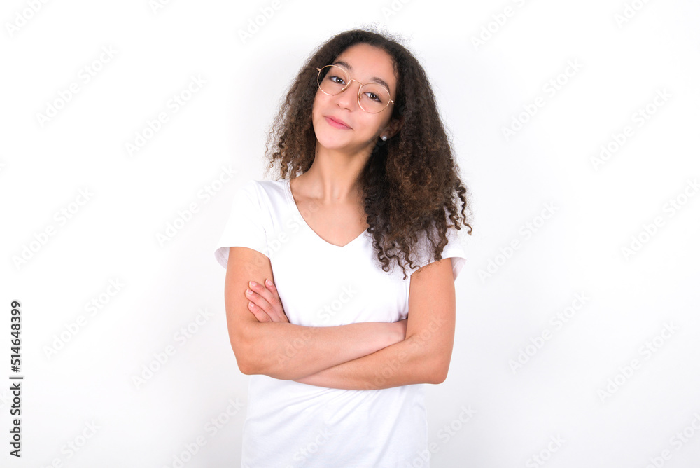 young beautiful girl with afro hairstyle wearing white t-shirt over white wall being happy smiling and crossed arms looking confident at the camera. Positive and confident person. young beautiful girl with afro hairstyle wearing white t-shirt over white wall being happy smiling and crossed arms looking confident at the camera. Positive and confident person.