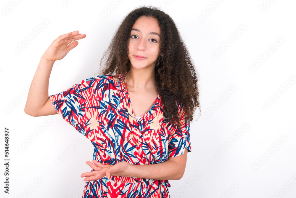 young beautiful girl with afro hairstyle wearing flowered dress gesturing with hands showing big and large size sign, measure symbol. young beautiful girl with afro hairstyle wearing flowered dress gesturing with hands showing big and large size sign, measure symbol.