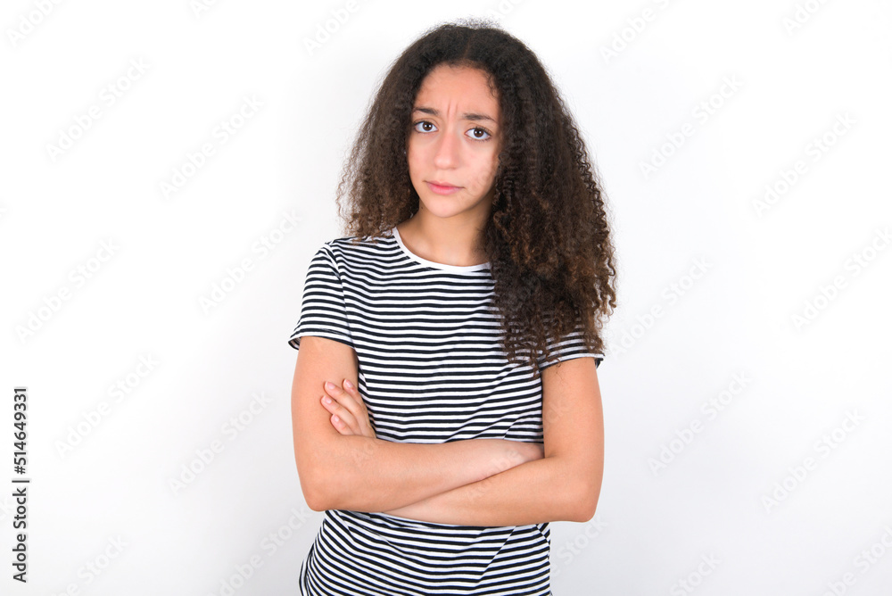 Picture of angry young beautiful girl with afro hairstyle wearing striped t-shirt over white wall looking camera. Picture of angry young beautiful girl with afro hairstyle wearing striped t-shirt over white wall looking camera.